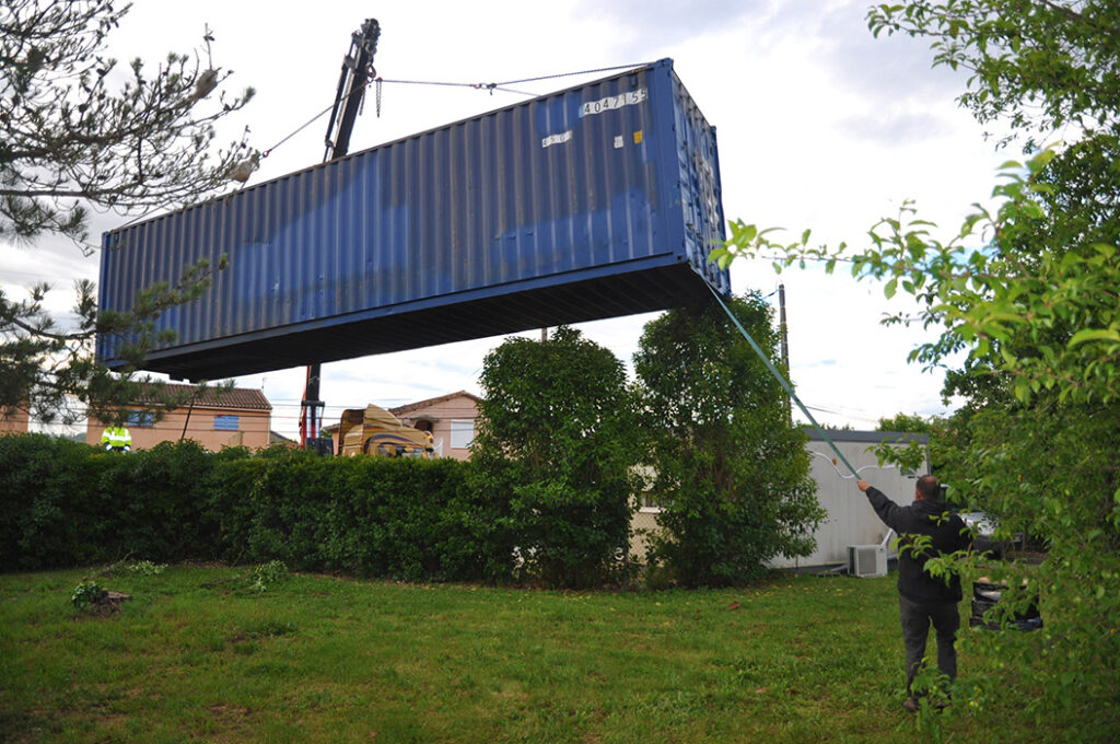 Installation d'un container maritime au moyen d'une grue, en vue d'être transformé en salon de coiffure design.