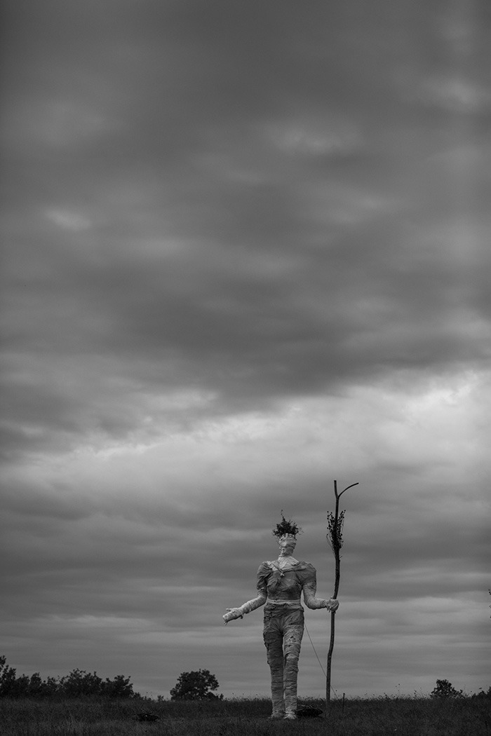 Photographie en noir et blanc de la Pèlerine marchant sur les terres du Comminges à l'occasion de l'événement musical l'Homme sauvage 2022. Création Alexandra Drabzak.