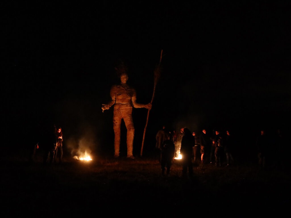 Photographie de nuit de la Pèlerine avec public réunis autour de braseros.