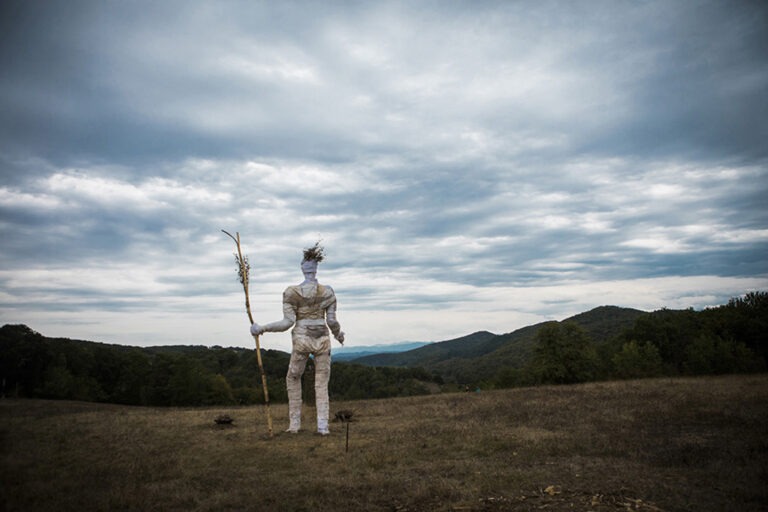 Photographie de la pèlerine de dos devant le paysage du Comminges. Création d'Alexandre Drabzak à l'occasion de l'événement musical l'Homme sauvage 2022.
