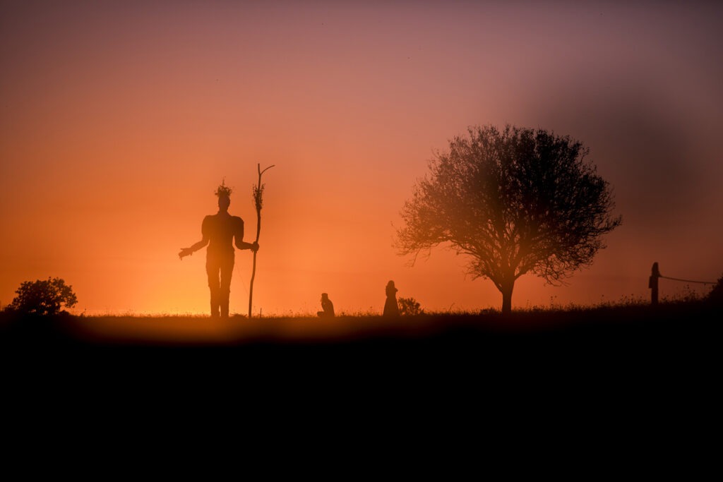 Photographie de la Pèlerine au coucher du soleil, avec silhouettes de visiteurs sur fond de ciel couleur saumon.