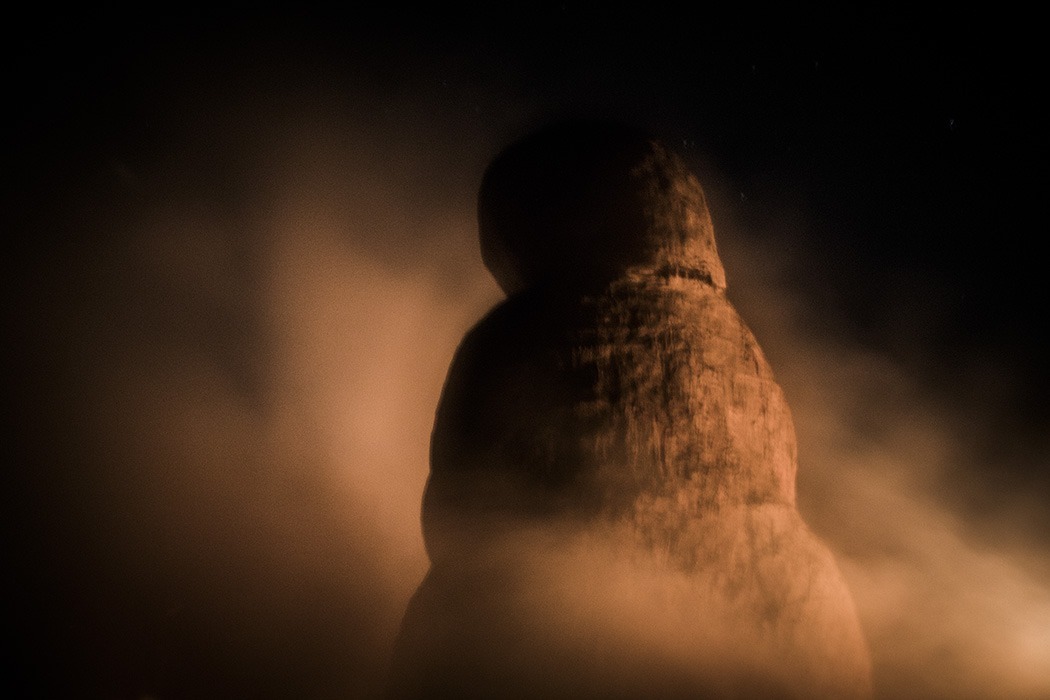Prise de vue artistique de la Vénus de terre monumentale vue de dos de nuit avec des effluves de fumée l'entourant.