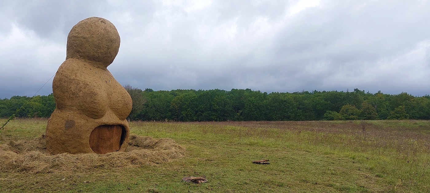 Photographie de la Vénus monumentale en terre cru, à son premier jour, dans un décors de prairie et de bois,