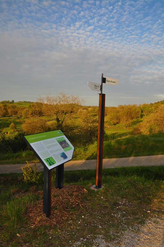 Lutrin pédagogique et mât directionnel designs associant bois et métal, conçus pour une parcours de golf écologique. 