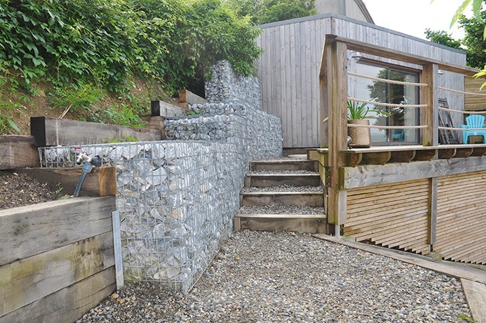 Photographie montrant le point de croisement du jardin avec à gauche l'accès au pool-house et à la terrasse supérieure, et à droite le haut du grand escalier menant à la grande terrasse et sa piscine. 