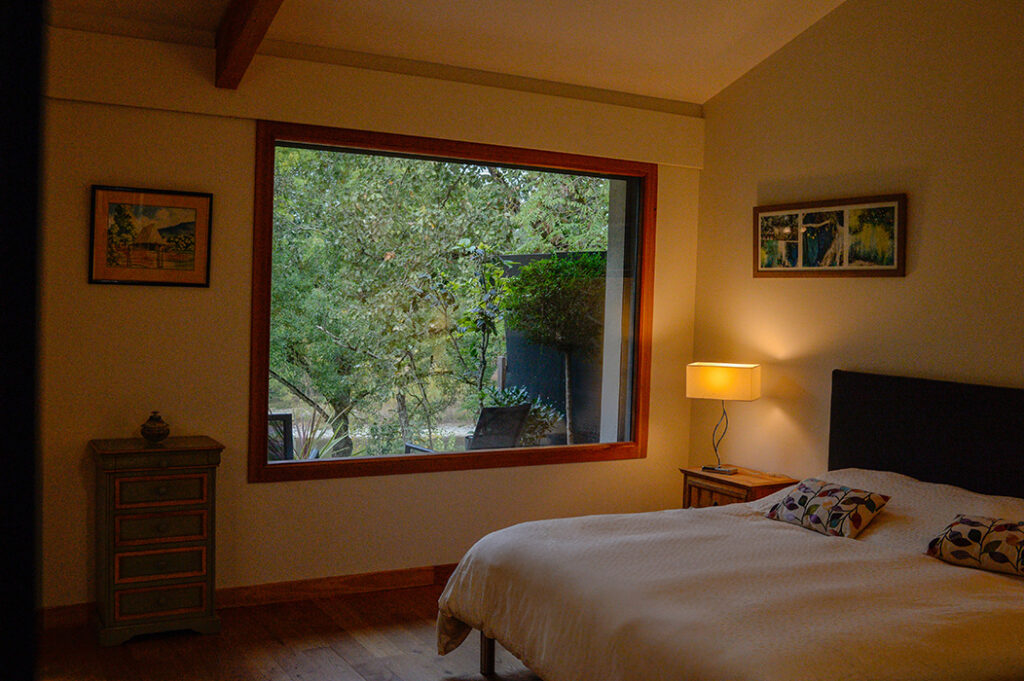 Photographie de la chambre principale avec le lit et la grande baie fixe donnant vue sur le fleuve Garonne.