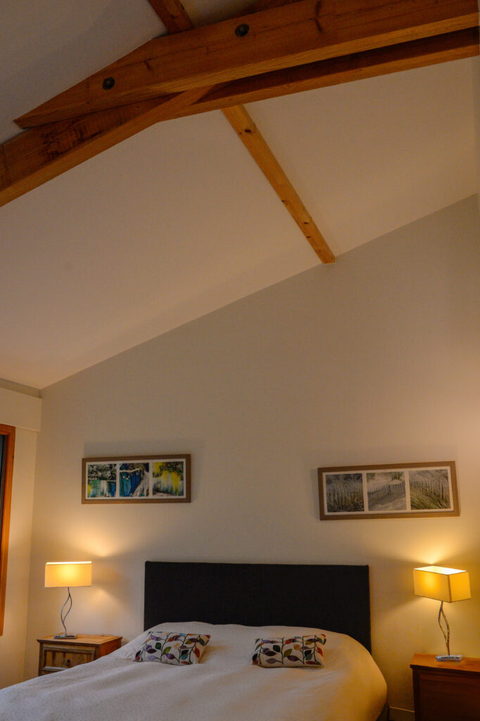 Photographie de la chambre avec son plafond haut en rampant et sa charpente apparente.