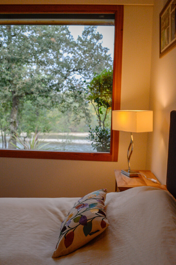 Photographie de la chambre prise depuis le lit, avec grande baie donnant vue sur le fleuve.