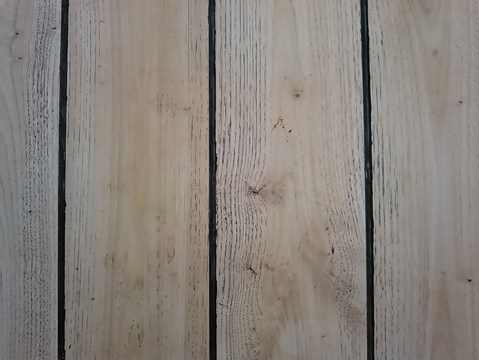 Photographie du plancher "pont de bateau" de la salle de bain en détails.