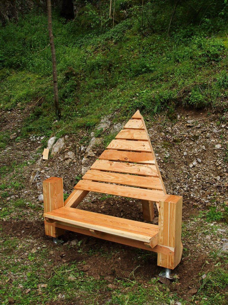 Banc design en bois en forme de triangle et installé à proximité d'un parcours ludique, pédagogique et sportif de pleine nature.