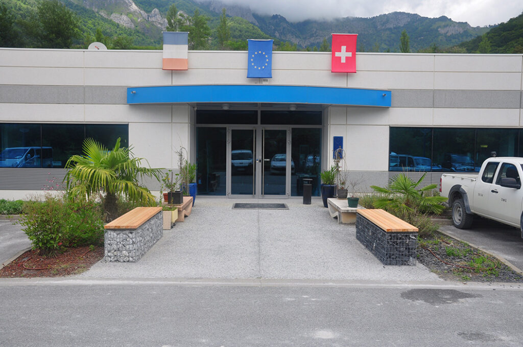 Banc-Gabion constitué d'une assise en bois fixée sur un gabion (cage de métal rempli de pierre), installé devant les locaux d'OMG.