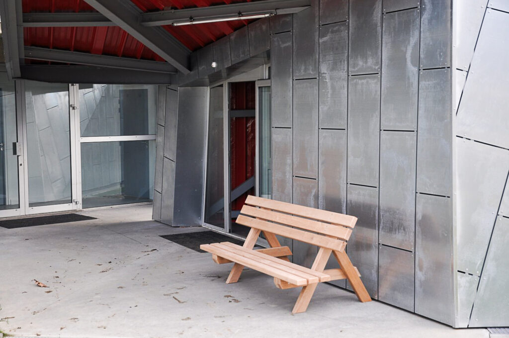 Banc en bois design installé devant un édifice moderne couvert de plaque de métal.