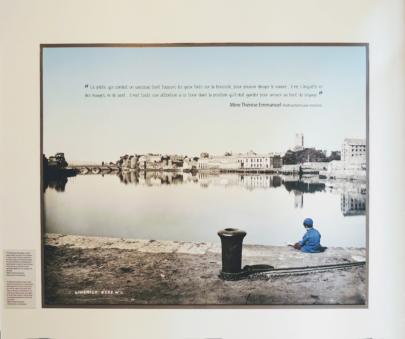 Ancienne photographie de Limerick en Irlande (lieu d'origine de Mère Thérèse-Emmanuel), représentant un port, la ville en arrière plan et un petit garçon assis au bord du quai. La photographie a été colorisée (ciel et son reflet dans la baie, ainsi que les vêtements du petit garçon). La photographie comprend une citation célèbre de Mère Thérèse-Emmanuel très en lien avec la batellerie : "Le pilote qui conduit un vaisseau tient toujours les yeux sur la boussole, pour pouvoir diriger le navire. Il ne s'inquiète ni des nuages, ni du vent. Il met toute son attention à se tenir dans la position qu'il doit garder pour arriver au bout du voyage."