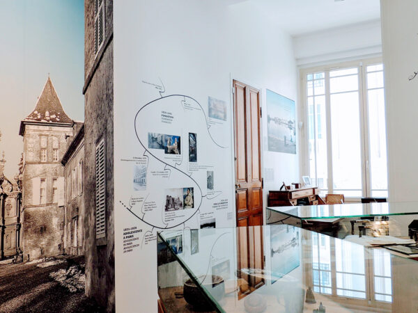Photographie en perspective du musée montrant plusieurs vitrine d'objets de souvenirs, la seconde partie de la frise historique, une part de la grande photographie du Château de Preisch (Lorraine) et sa chapelle, et le bureau de Mère Thérèse-Emmanuel.