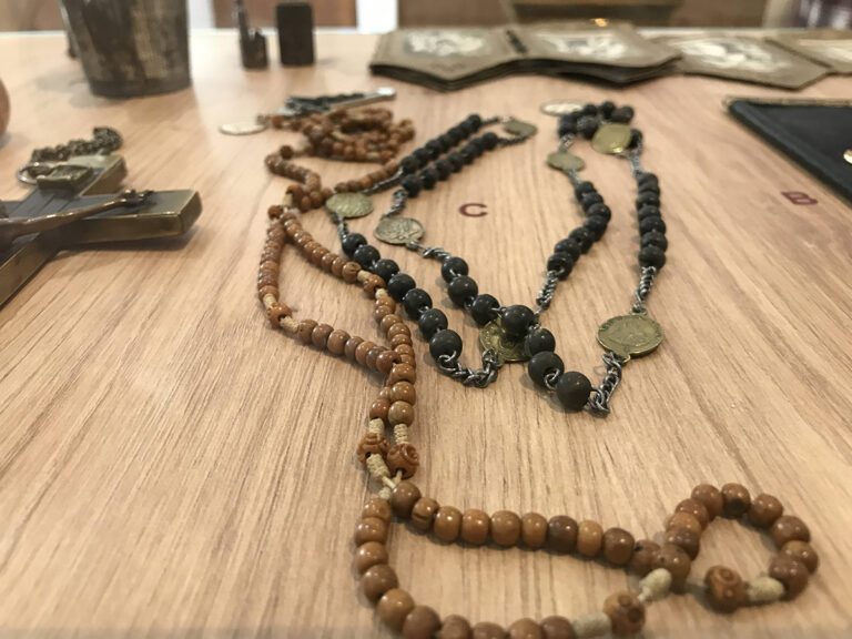 Zoom sur l'intérieur d'une vitrine et portant sur des chapelets anciens.