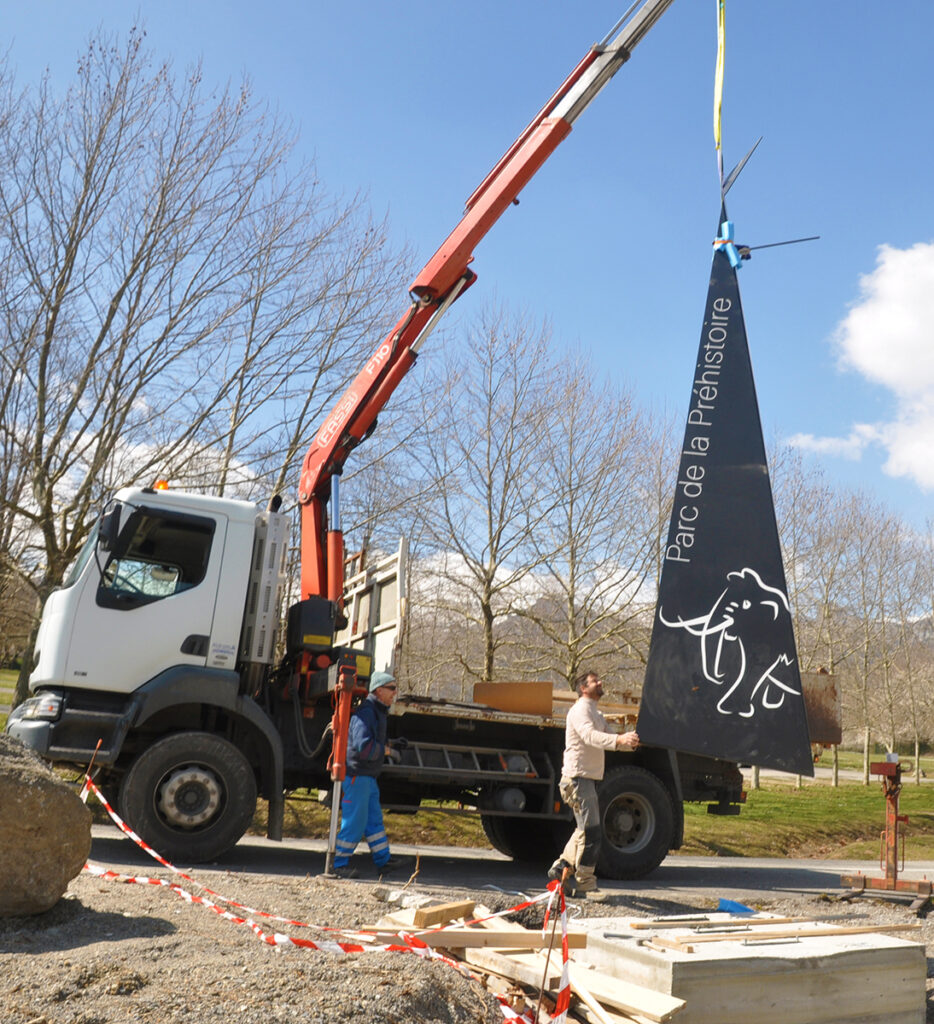 Installation du Grand totem en acier plié, marquant l'entrée du site du Parc de la Préhistoire.