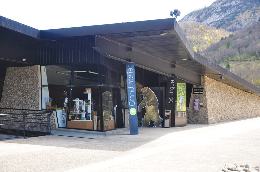 Photographie de signalétiques indiquant les différents espaces du bâtiment. Marquage en lettres blanches sur poteaux noirs.