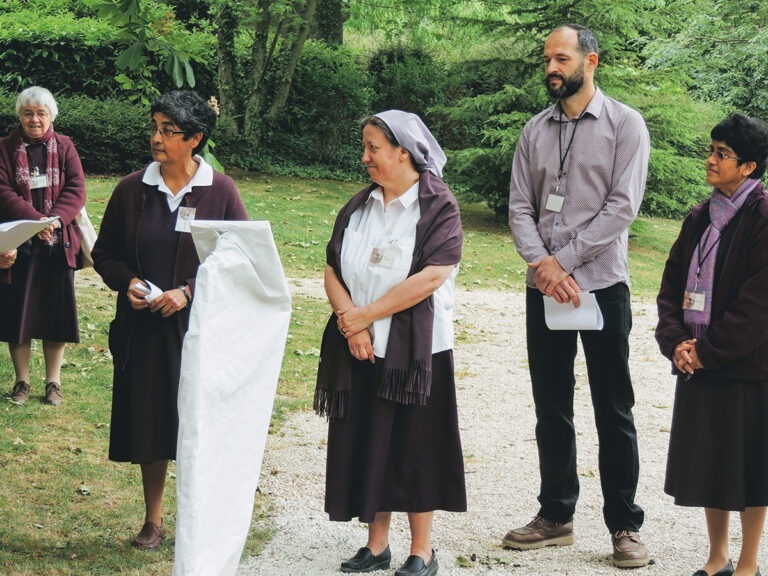 Photographie de la cérémonie d'inauguration du parcours précédant la présentation au public du lutrin design (masqué par un tissu blanc). Visible sur la photographie, de droite à gauche, Mère Rékha, Alexandre Drabzak (designer du Lutrin et co-concepteur du parcours), Sœur Véronique (co-conceptrice du parcours), et deux autres sœurs.