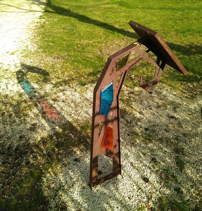 Photographie d'un lutrin et de son ombre projetée au sol, montrant des jeux de lumières dit d'"ombre colorée", permis par des vitraux bleu et rouge. Design et concept par Alexandre Drabzak.