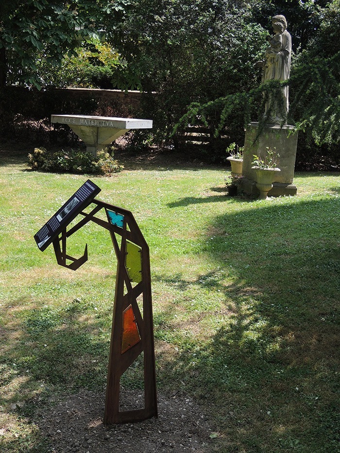 Photographie d'un lutrin installé dans le parc d'un couvent, proche d'un autel et d'une statue.