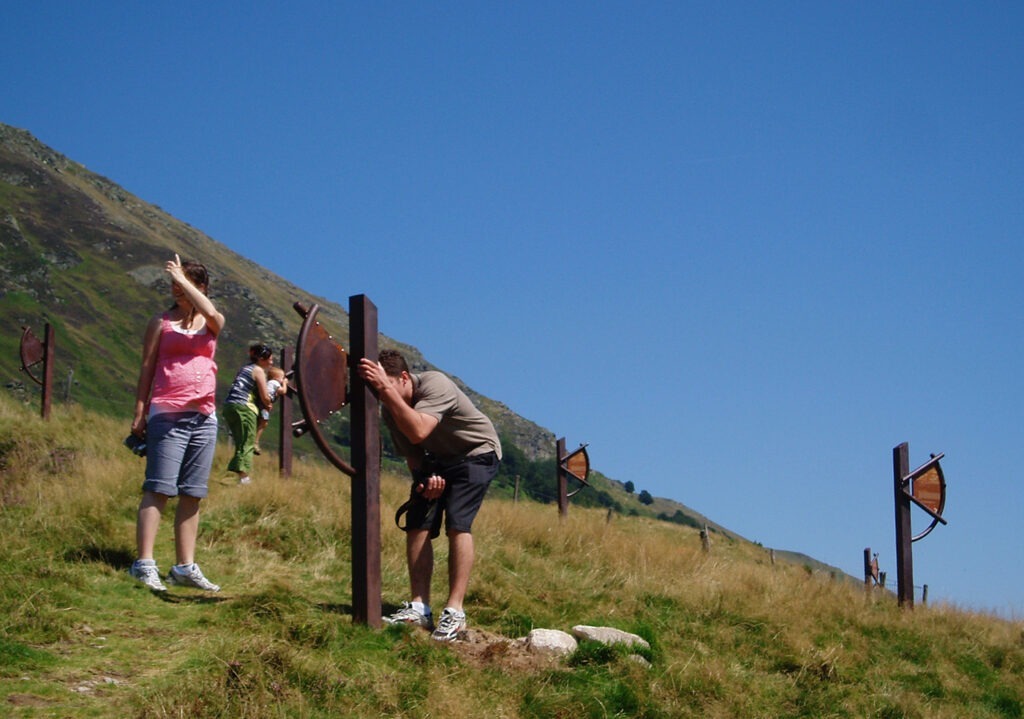 Photographie d'un groupe de personne utilisant le Sextant du Plateau de découverte du Col de la Core en Ariège (Pyrénées), pour viser un élément précis du paysage. 