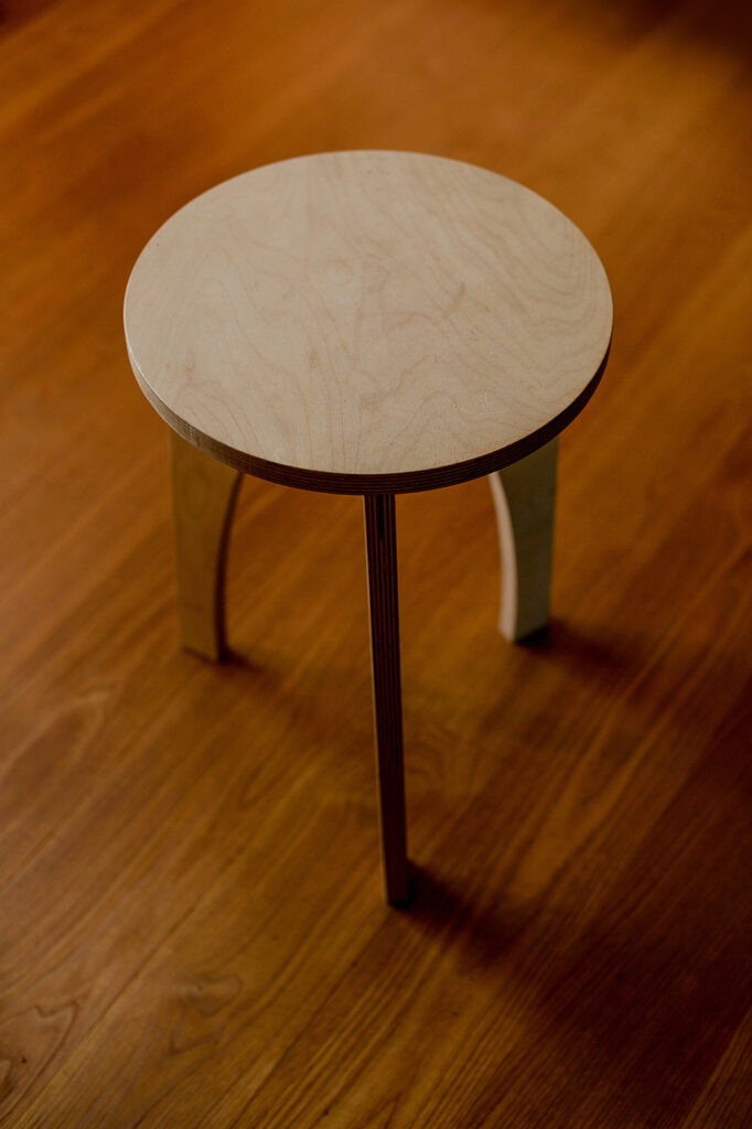 Photographie d'un tabouret en bois DIY (à monter sous-même) posé sur une plancher en bois. 