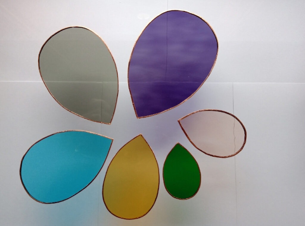 Vitraux de différentes couleurs et tailles, découpées en forme de goutte d'eau et sertis de cuivre.