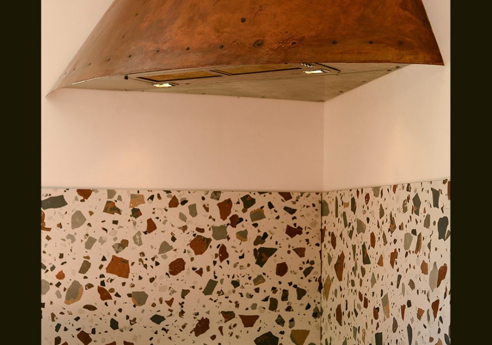 Hotte de cuisine design de style Steampunk, fait d'un manteau de cuivre avec des lignes de cous de cuivre visible. Le dessous de la hotte est en zinc. Le dispositif de filtration est un ancien système semi-professionnel récupéré et adapté.